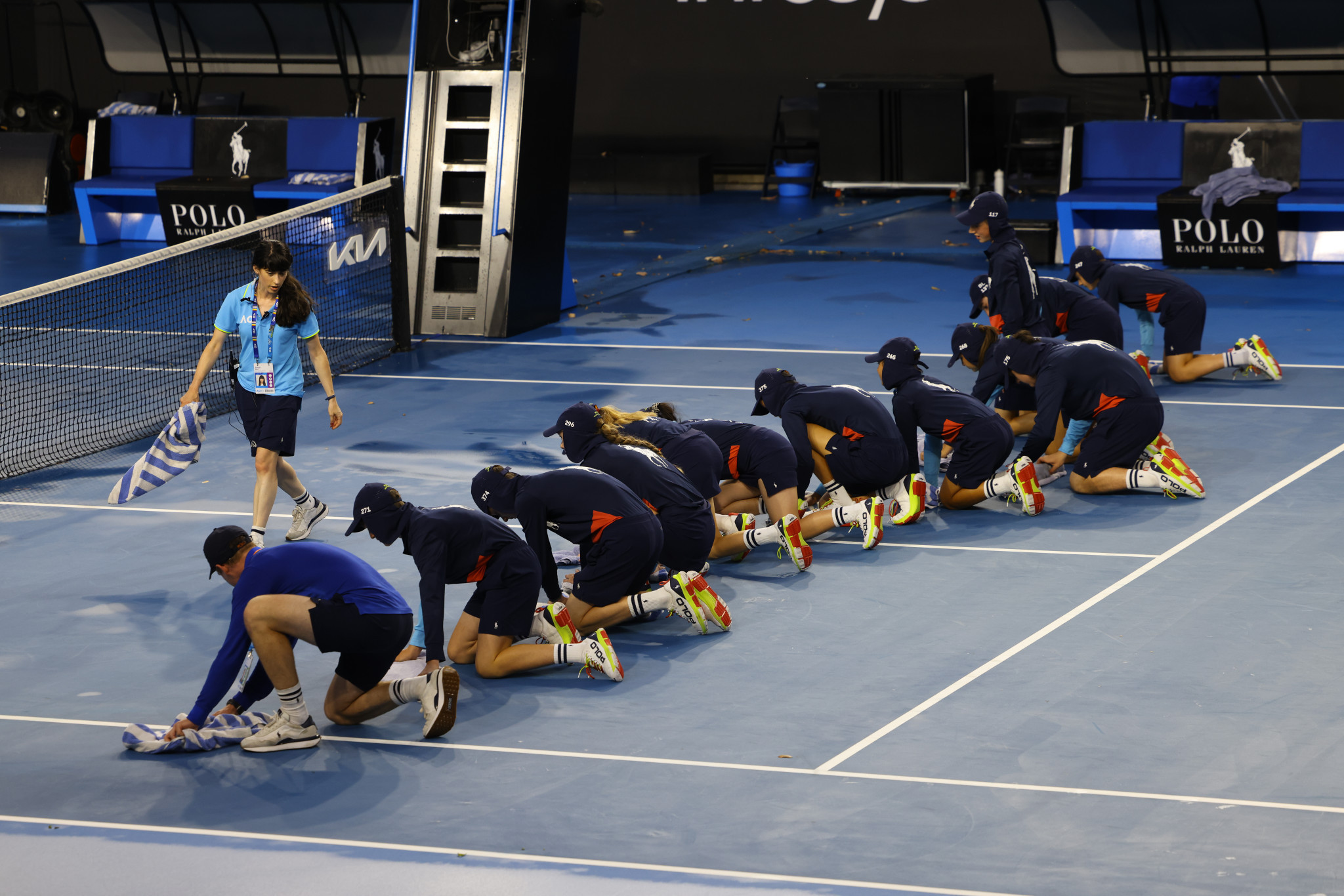 Ballkids use towels to wipe the courts following a heavy rain shower at Melbourne Park ©Getty Images
