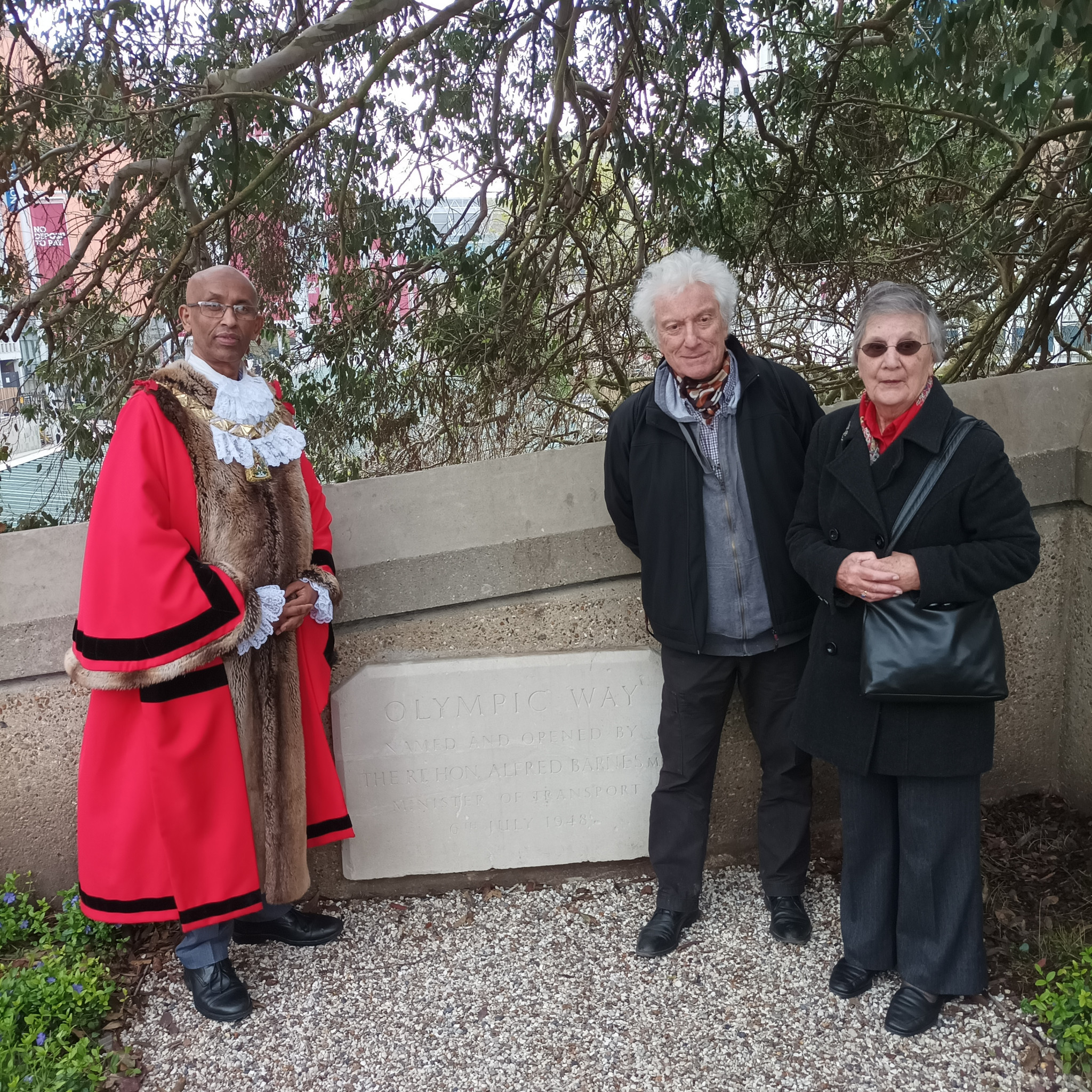 Wembley Mayor Abdi Aden, left, joins author Mike Collett and Margaret Winter, daughter of the engineer who built Olympic Way, at a ceremony to restore a commemorative plaque from 1948 ©ITG