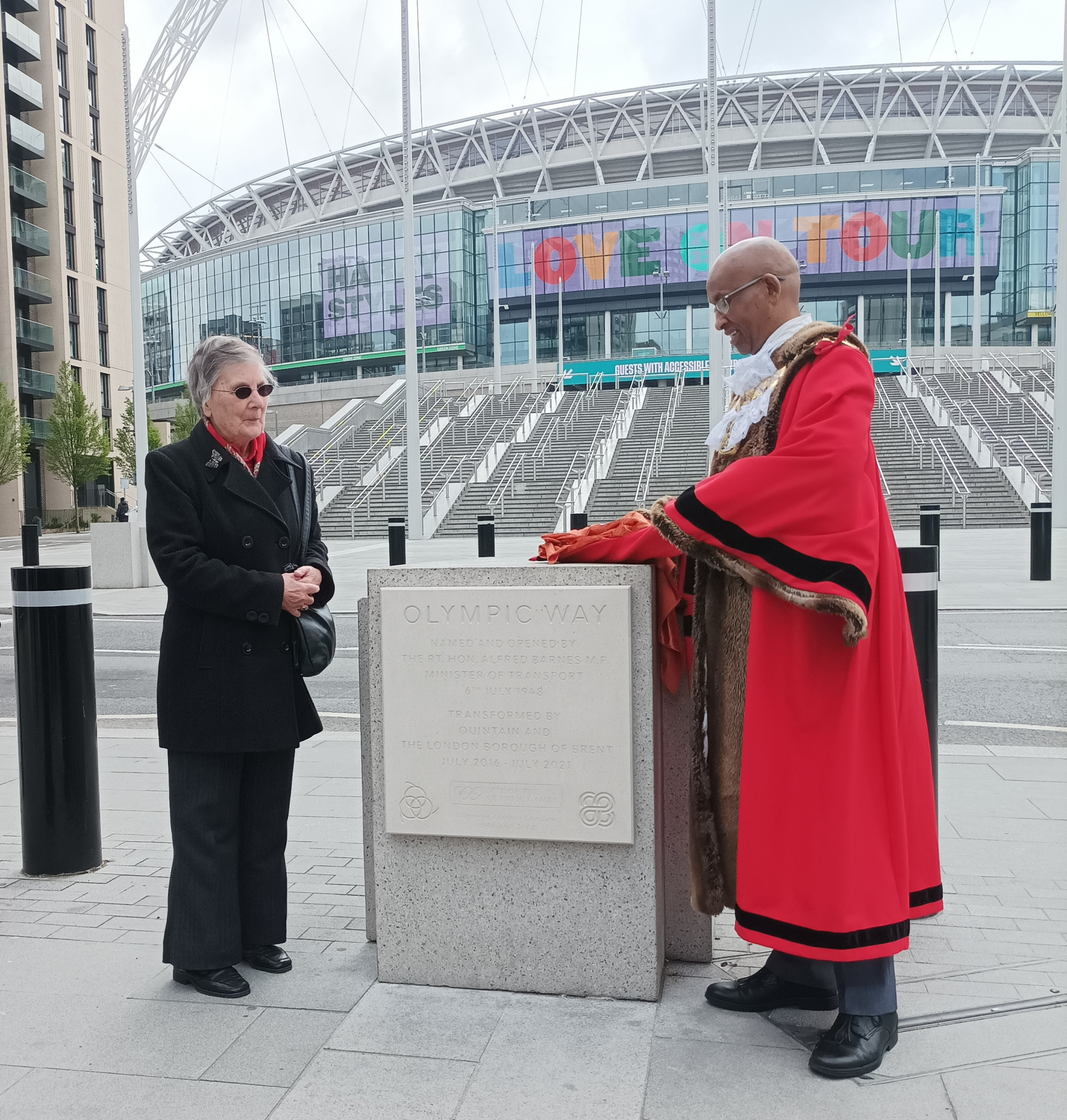 Wembley Mayor Abdi Aden unveils the new plaque accompanied by Margaret Winter, daughter of Walter Steedman, the engineer who designed Olympic Way ©ITG
