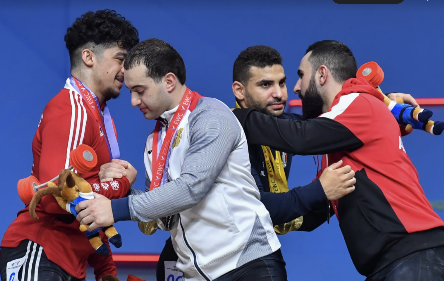 Turkish and Armenian lifters embrace each other on the podium following the men's 81 kilograms category ©Brian Oliver