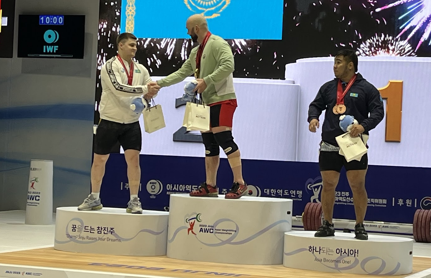 Artyom Antropov, left, shakes hands with gold medallist Ruslan Nurudinov on the podium for the men's 109kg category at the Asian Weightlifting Championships ©Brian Oliver