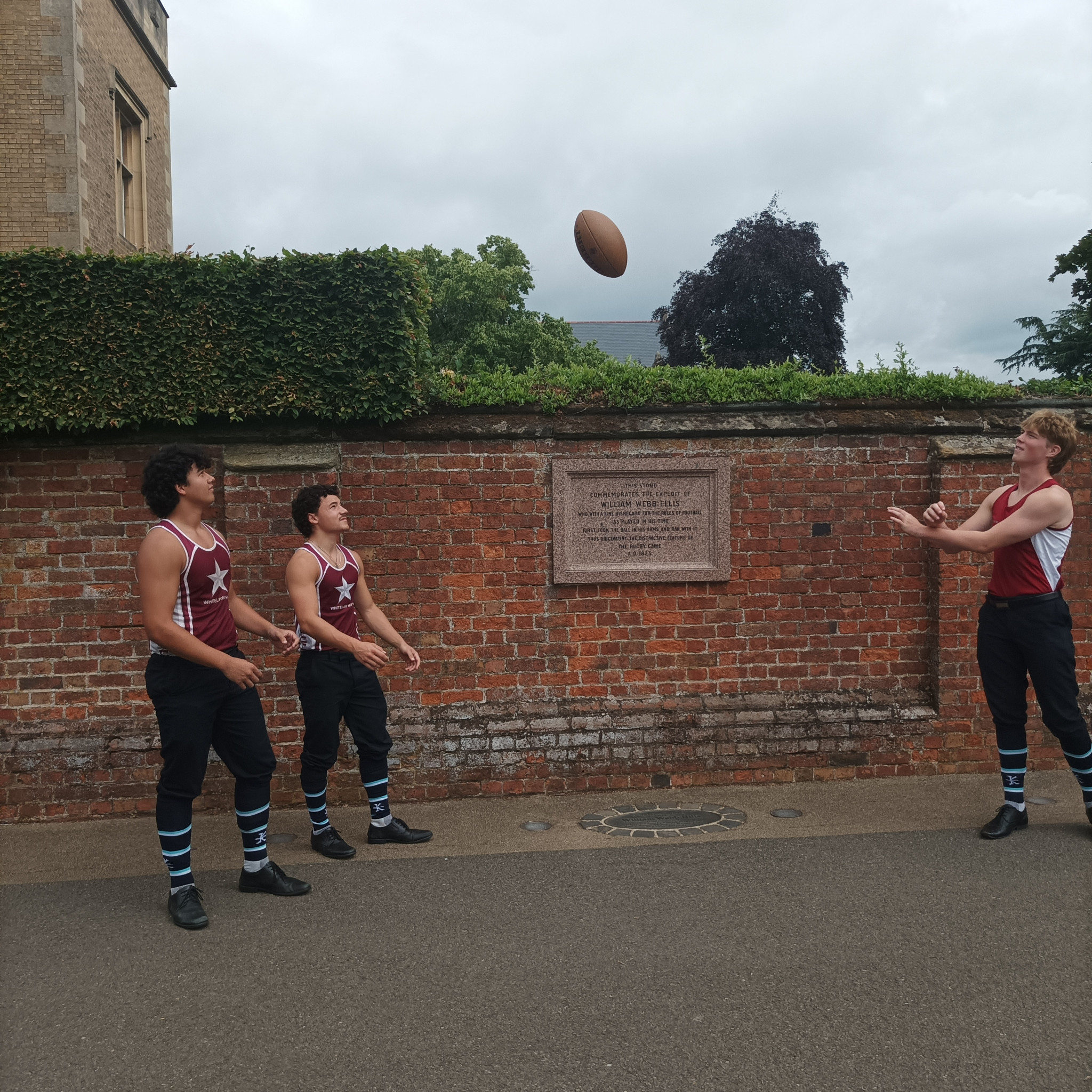 Pupils throw a rugby ball in front of tablet honouring William Webb Ellis at Rugby School ©ITG
