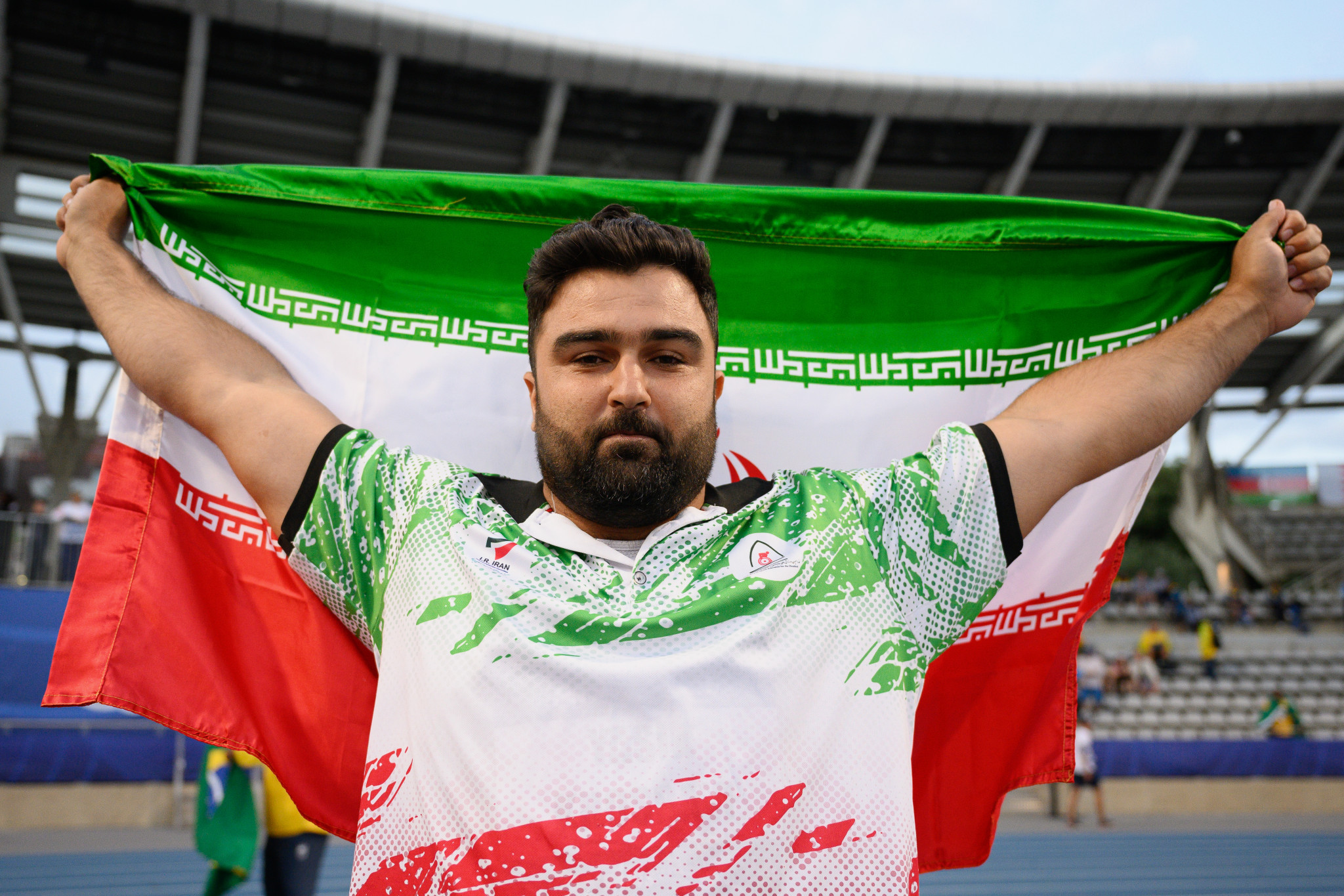 Yasin Khosravi celebrates with the Iranian flag after winning gold in a world record in the men's shot put F57 ©Getty Images