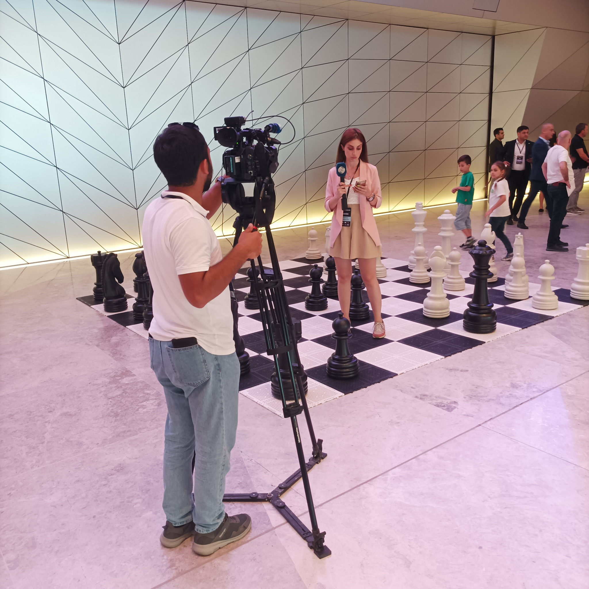 A television reporter on a giant chess board at the Baku Convention Center © ITG