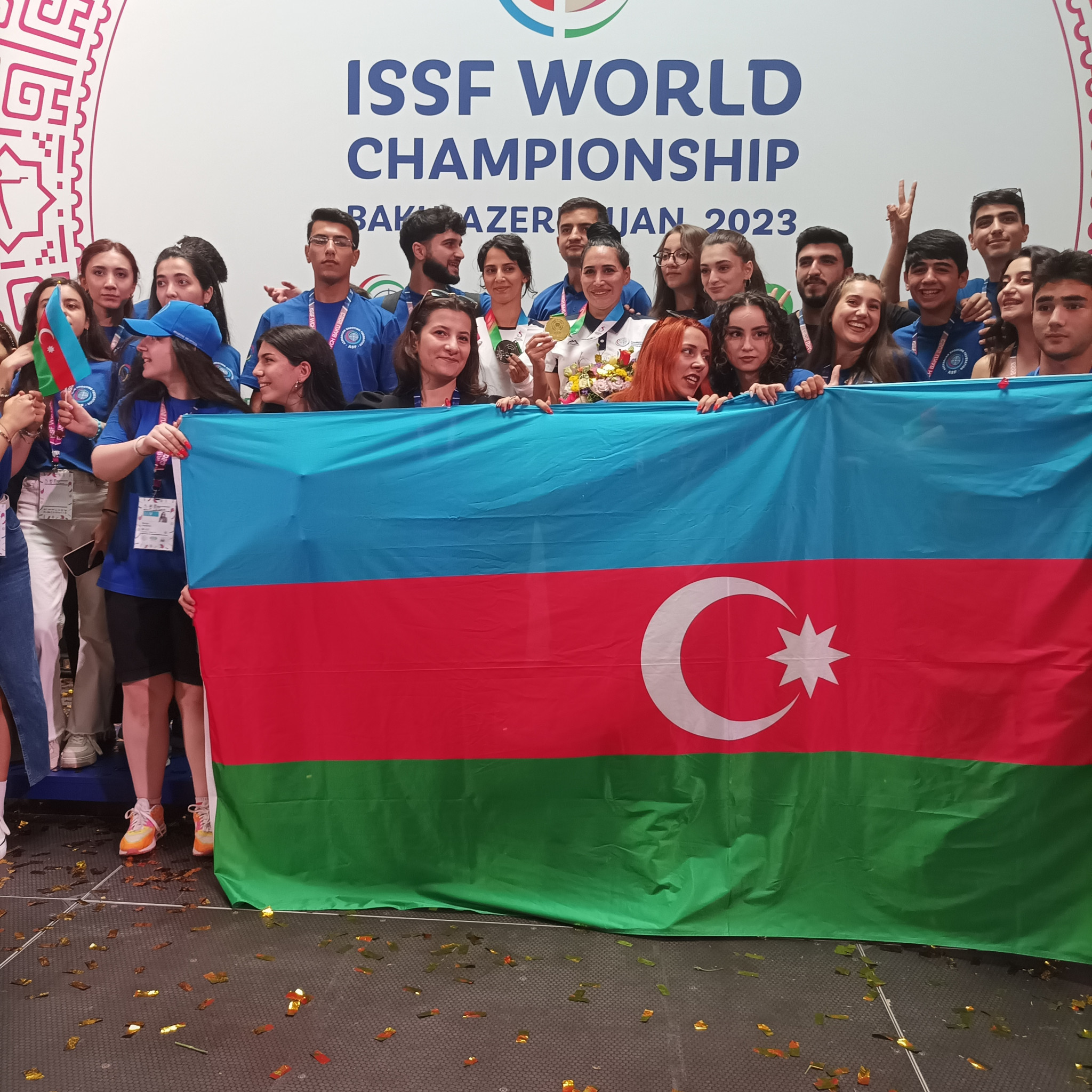 Azerbaijan's gold and silver medallists are almost hidden as volunteers join them on the podium to celebrate their success ©ITG