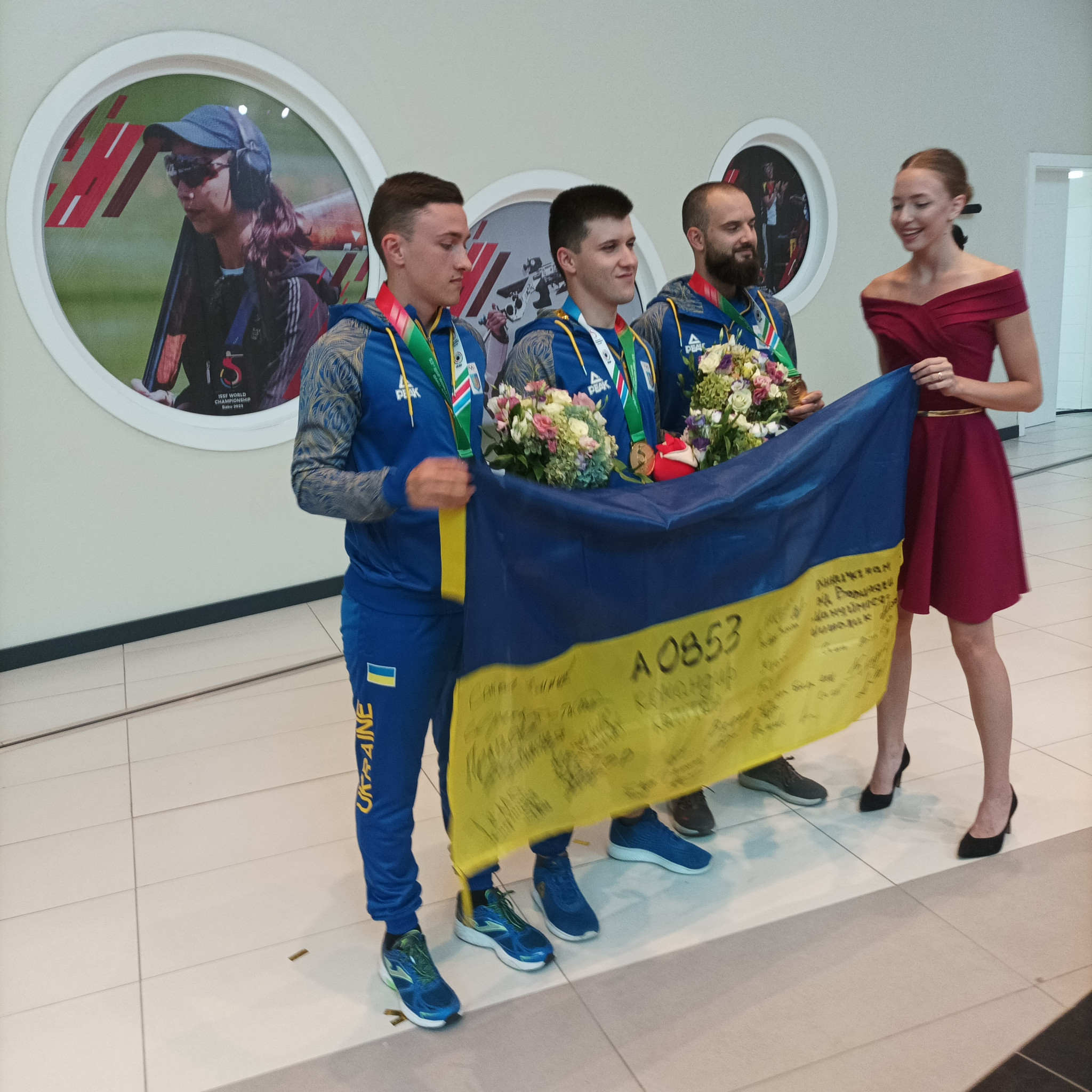 Ukraine celebrate gold medals and display flag with messages from the front at ISSF World Championships