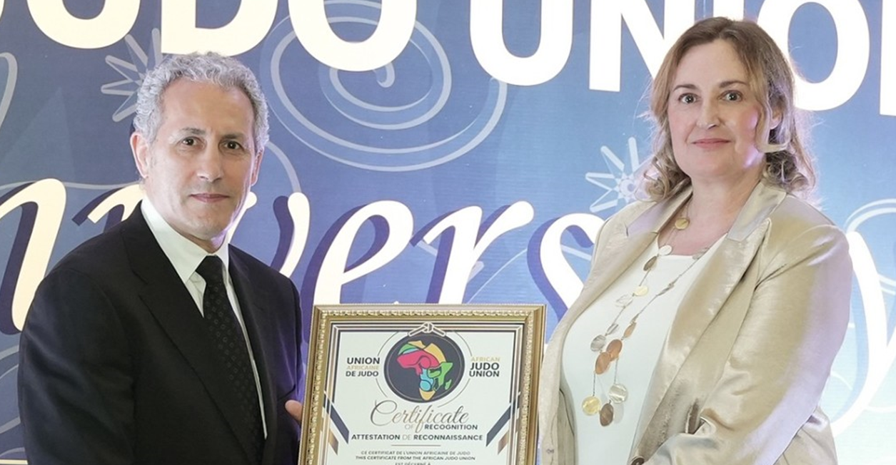 Lisa Allan, the IJF secretary general, accepts an award on behalf of IJF President Marius Vizer from Mohamed Meridja, the first vice-president of the African Judo Union, at the latter organisation's 60th anniversary ceremony ©IJF