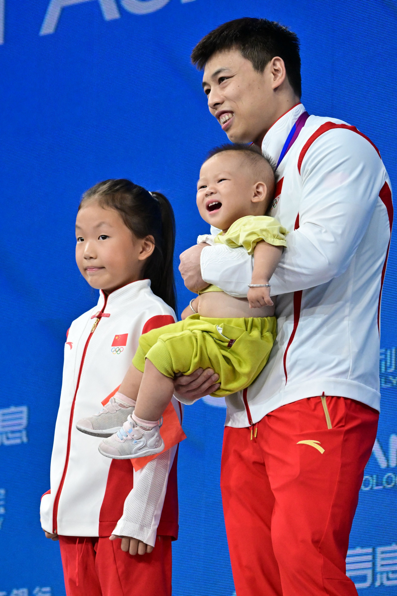 Chen Lijun is joined on the podium by his children to celebrate his victory in the men's 67kg category ©Getty Images