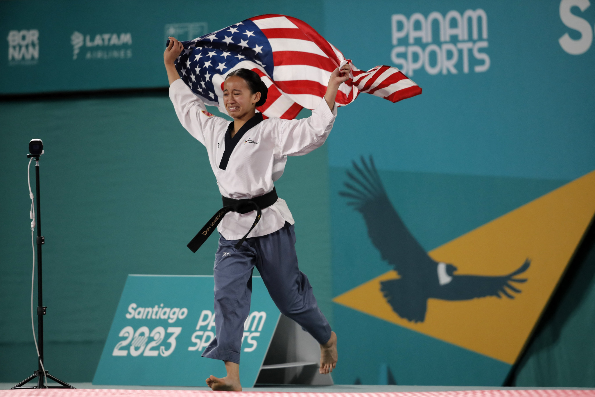 Kaitlyn Reclusado holds the United States flag as she celebrates her women's individual poomsae success ©Getty Images