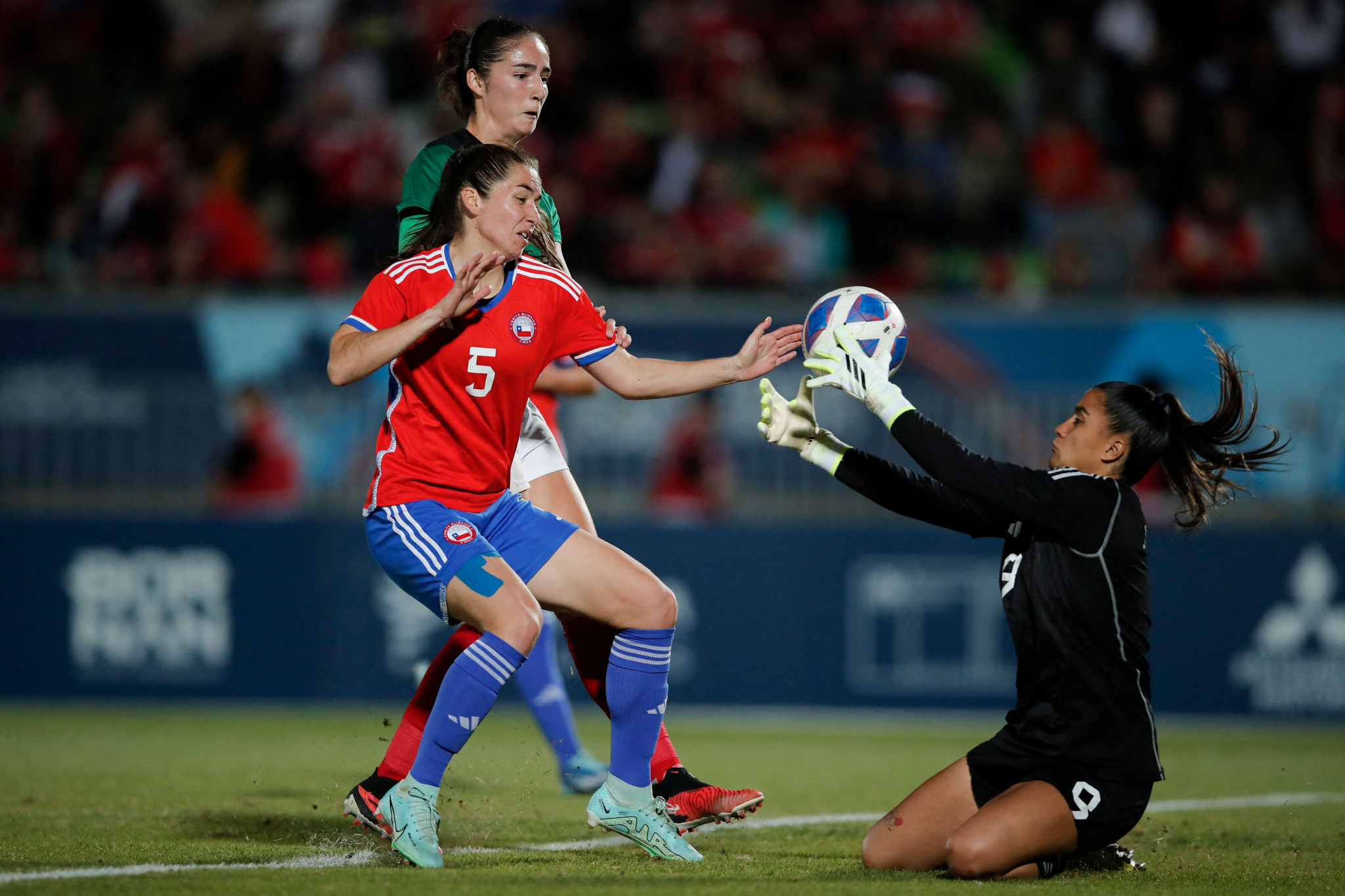 Chile's goalkeeper Maria Jose Urrutia (R) and defender Fernanda Ramirez (L) fight for the ball with Mexico's defender Diana Ordoñez during the women's team gold medal football match between Mexico and Chile at the Pan American Games Santiago 2023. © Getty Images