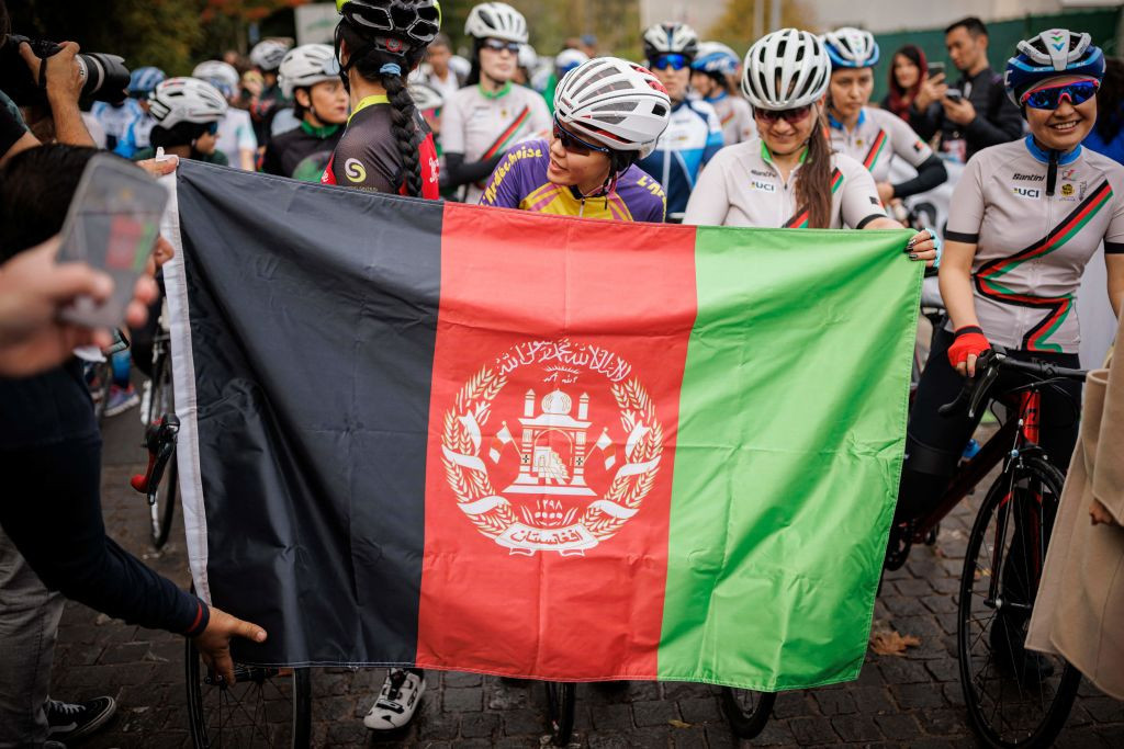 Masomah Ali Zada, the first Afghan cyclist participated in the Olympic Games as a member of the International Olympic Committee refugee team, behind an Afghan flag © Getty Images