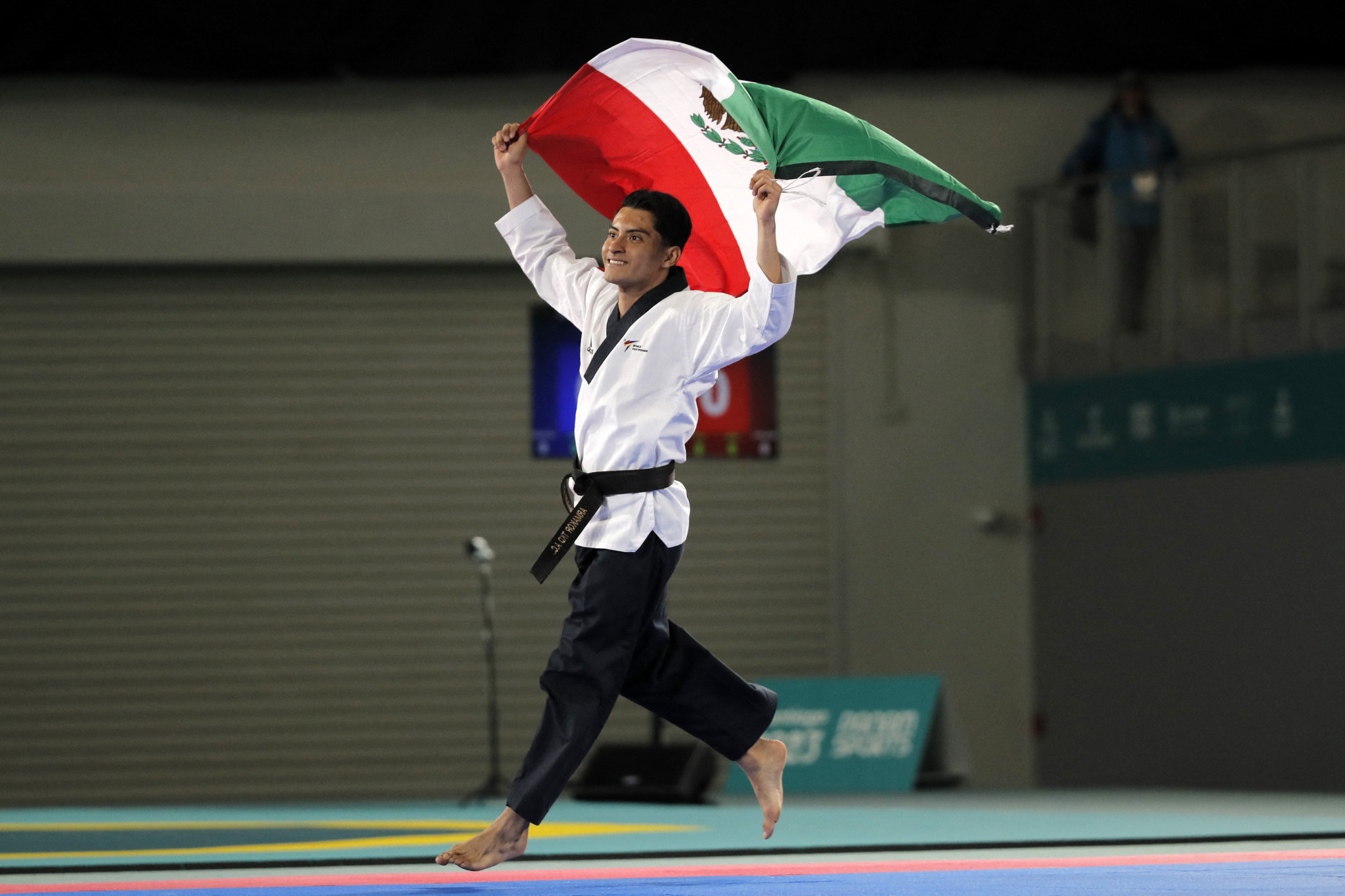 Mexico's William Arroyo holds the national flag after defeating Nicaragua's Elian Ortega to win the taekwondo men's individual poomsae final of the Pan American Games Santiago 2023 © Javier TORRES / AFP