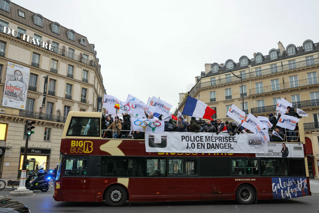 Protesters wave flags with a banner reading 'Police officers despised, Olympic Games in danger'. GETTY IMAGES