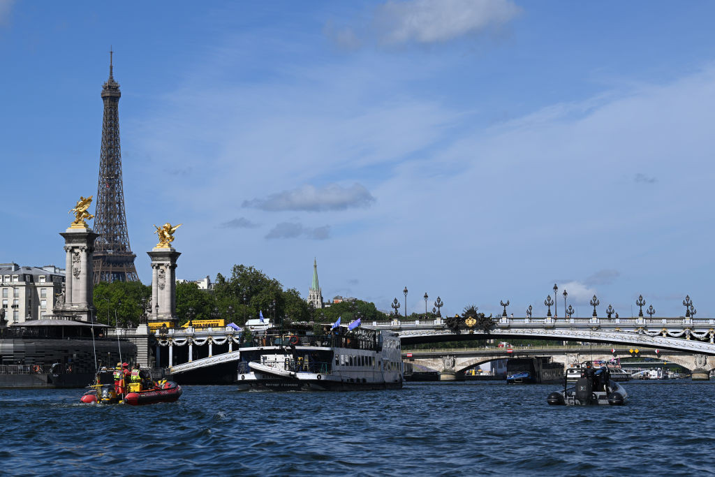 Volunteers wave flags aboard a boat on the Seine during the Paris 2024 technical test event. GETTY IMAGES