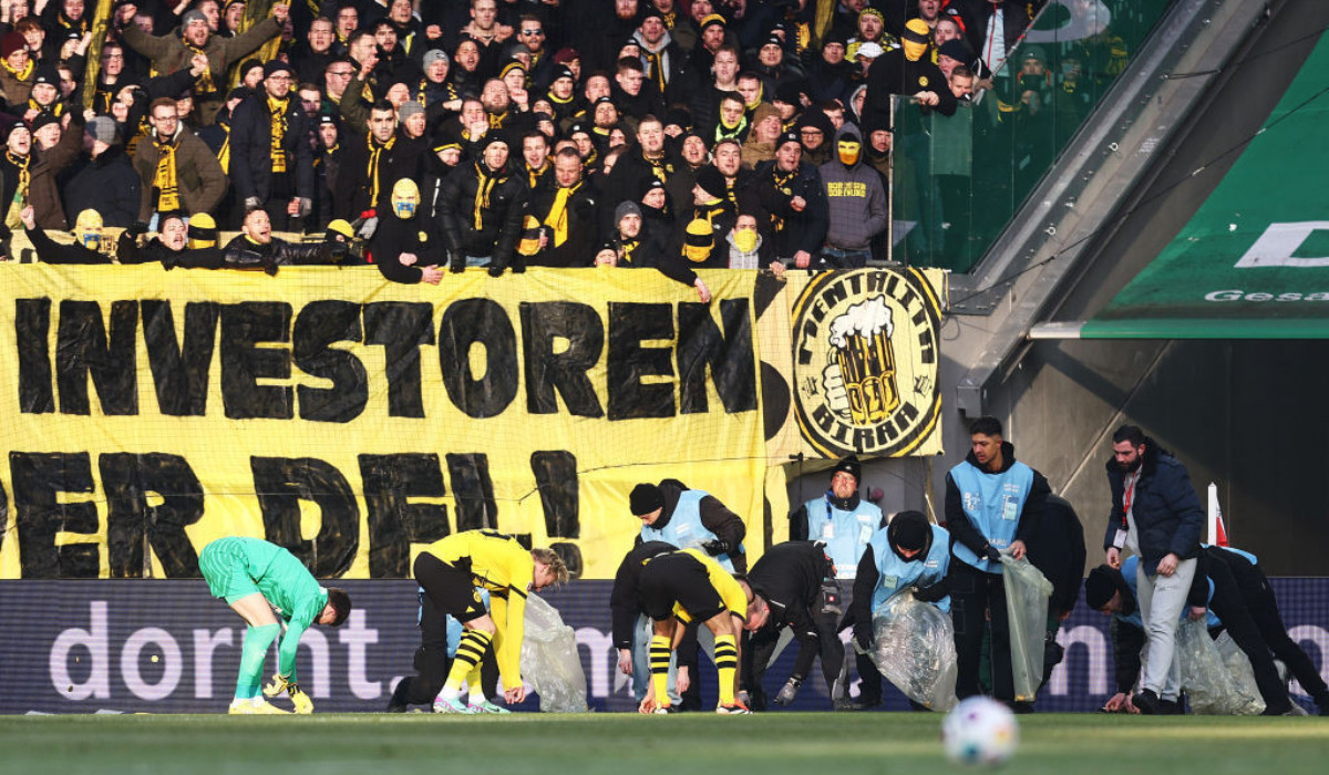 Borussia Dortmund players clear the pitch of chocolate coins thrown by protesting fans. GETTY IMAGES
