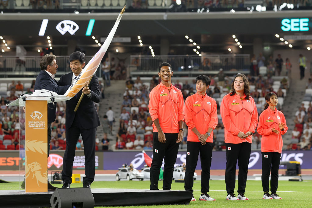 Coe presents a flag to Mitsugu Ogata, president of the Japan Association of Athletics Federations. GETTY IMAGES