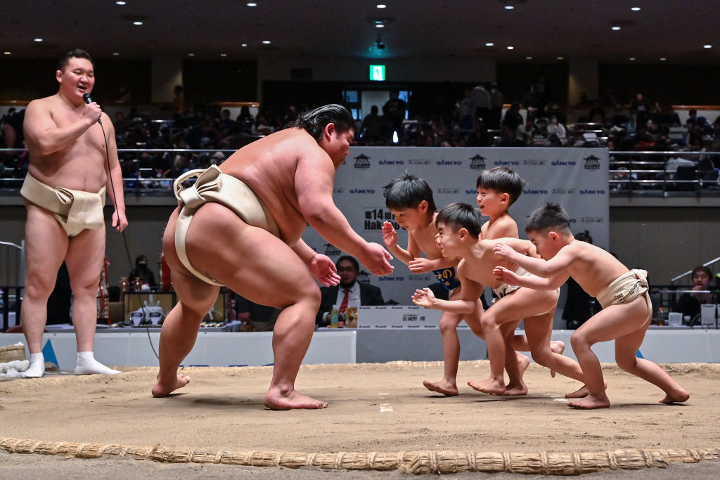  Hakuho watches as participants (R) try to push out Japanese wrestler Hakuoho (C) during a sumo class for youngsters on the sidelines of the 14th Hakuho Cup. GETTY IMAGES