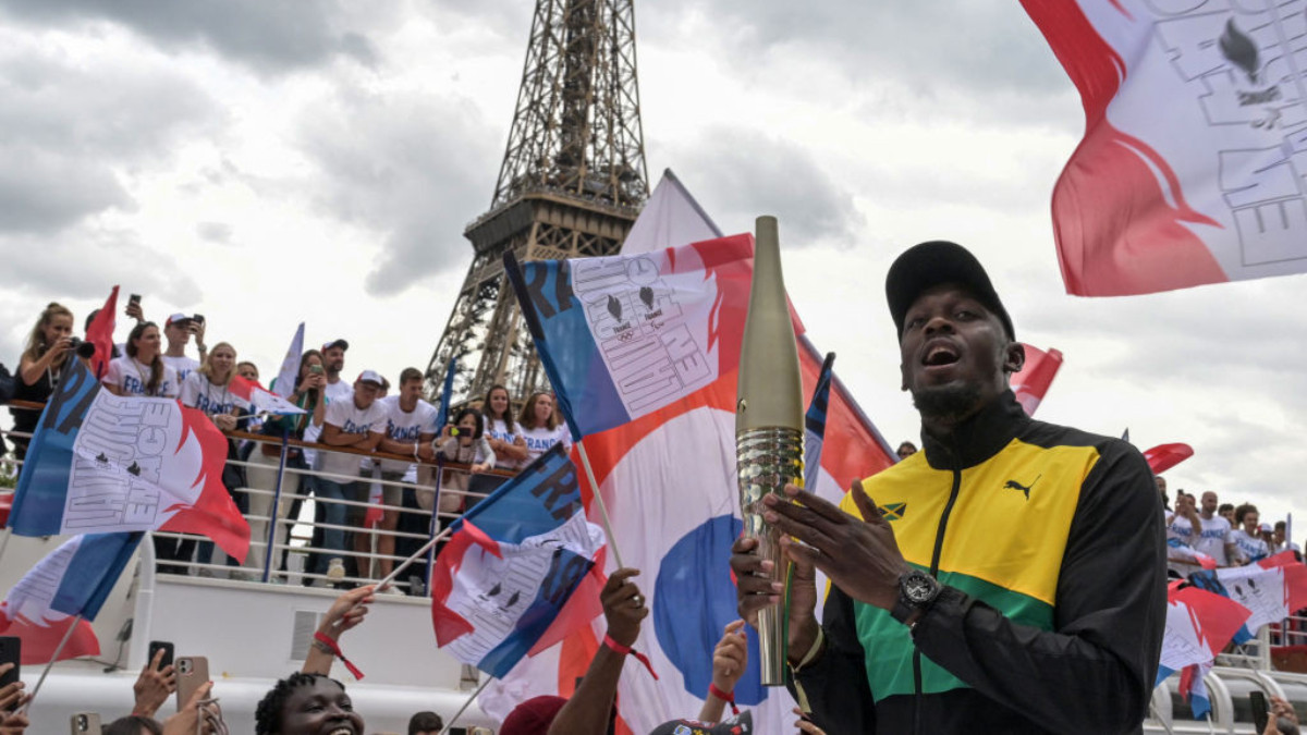 Usain Bolt holds the Olympic Torch on the Seine in Paris. GETTY IMAGES