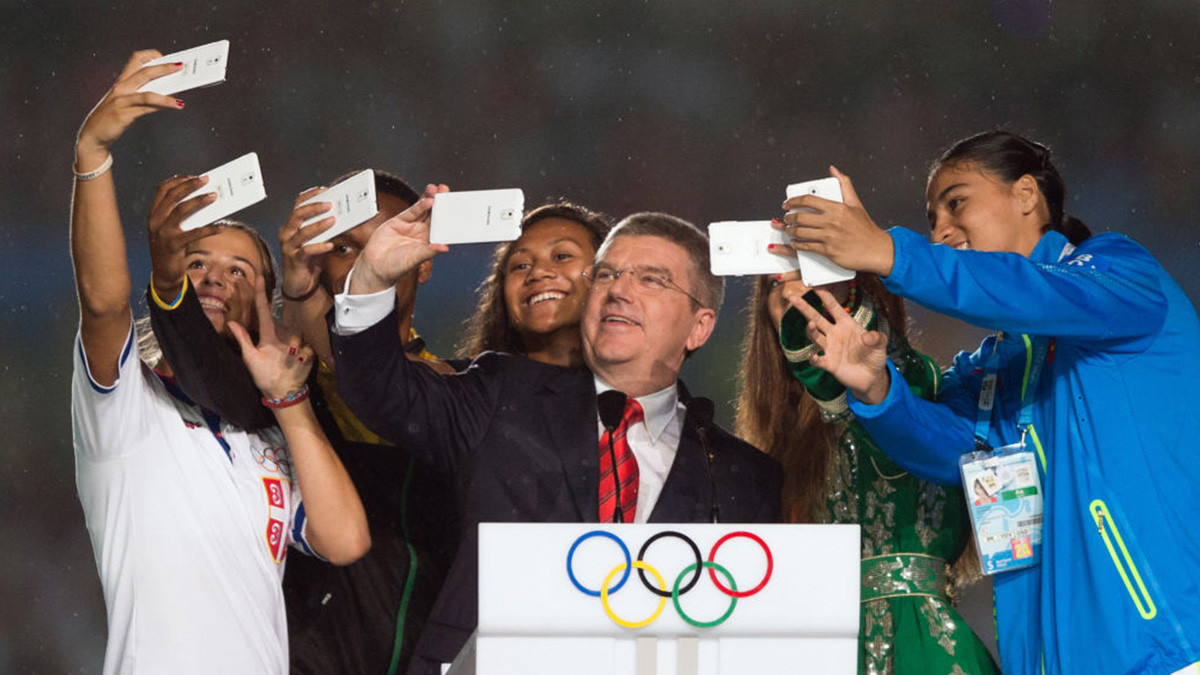 International Olympic Committee President Thomas Bach takes a selfie with athletes. GETTY IMAGES