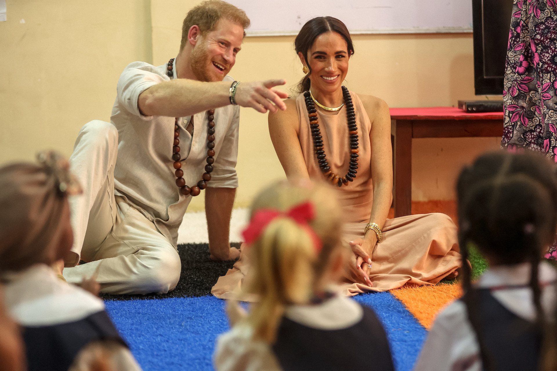 Britain's Prince Harry and Meghan Markle meet with children during their visit at the Lightway Academy in Abuja. GETTY IMAGES