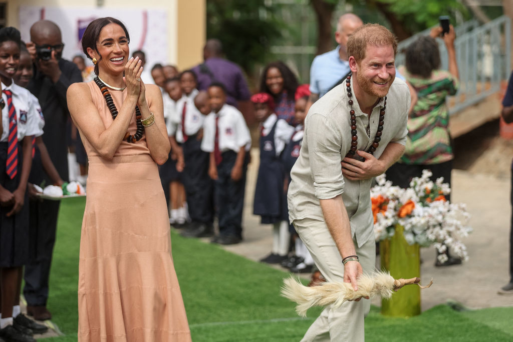 Prince Harry Meghan Markle take part in activities as they arrive at the Lightway Academy in Abuja, Nigeria. GETTY IMAGES
