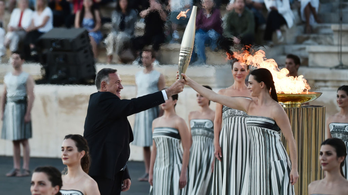 Spyros Capralos, receives the torch during the Olympic flame handover ceremony for the Paris 2024 at Panathenaic Stadium on April 2024. GETTY IMAGES