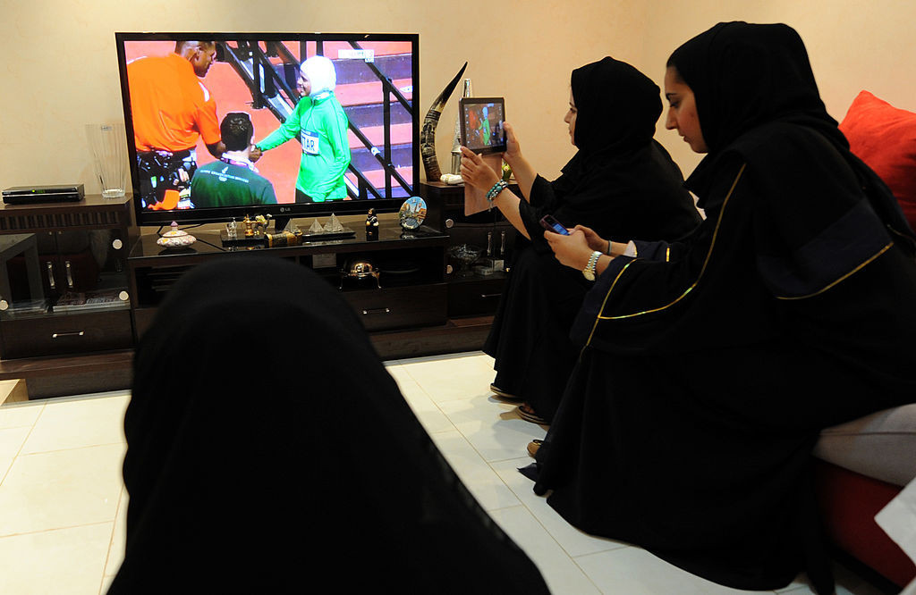 Saudi women sit in a house in Riyadh as they watch and film Saudi Arabia's Sarah Attar competing in the women's 800m heats. GETTY IMAGES