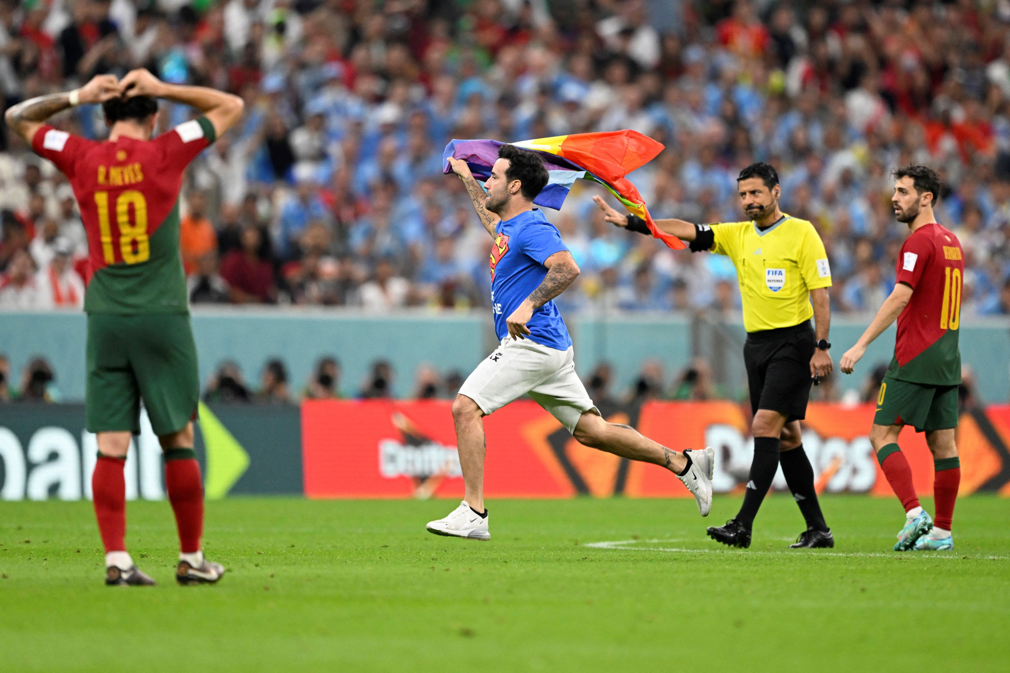 A protestor held up an LGBTQ+ flag at the 2022 World Cup in Qatar and wore a t-shirt donning 