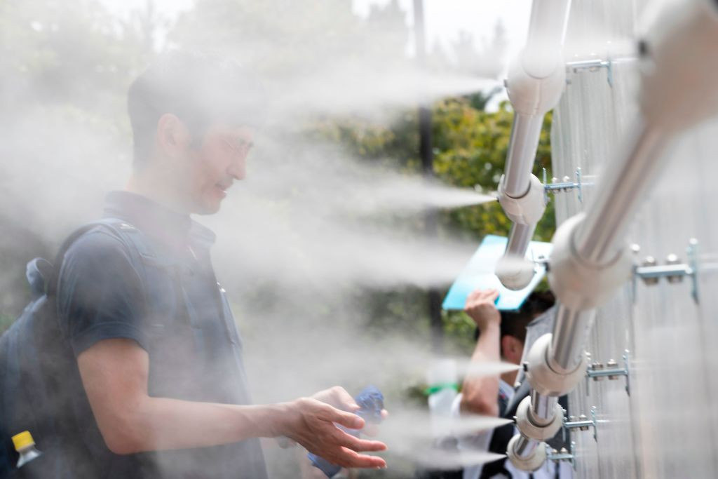 A man cools off at a mist station installed at Shiokaze Park during the beach volleyball test event for the Tokyo 2020 Olympic Games. GETTY IMAGES