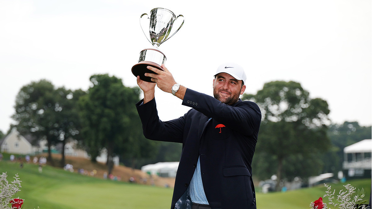 Scottie Scheffler poses with the trophy on the 18th green after putting in to win in a playoff during the final round of the Travelers Championship. GETTY IMAGES