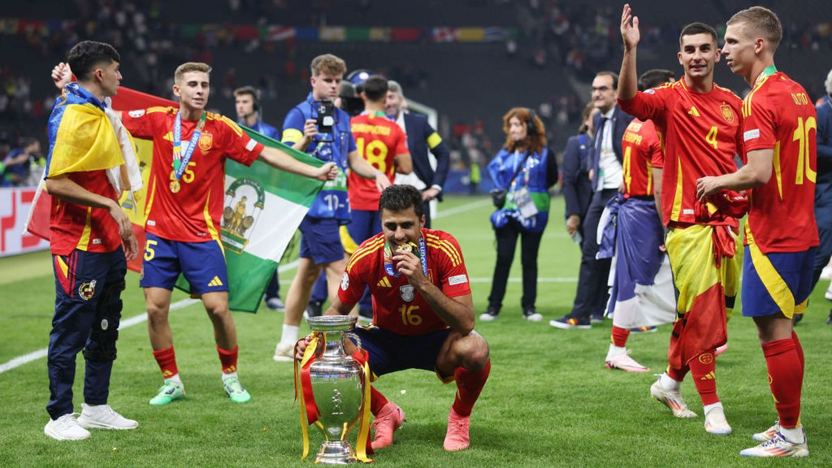 Rodri poses for a photo with the UEFA Euro 2024 Henri Delaunay Trophy as he bites his winners medal after victory in the UEFA EURO 2024. GETTY IMAGES