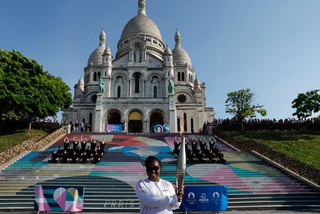 French Ivorian actress Claudia Tagbo poses with the Olympic torch in front of the Sacre-Coeur Basilica. GETTY IMAGES