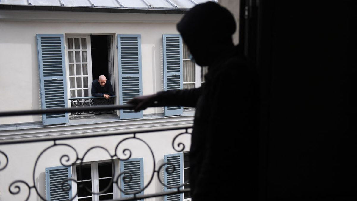 A neighbour looks on the street as migrants set up in an empty building, formerly business offices, in the 9th arrondissement of Paris. GETTY IMAGES
