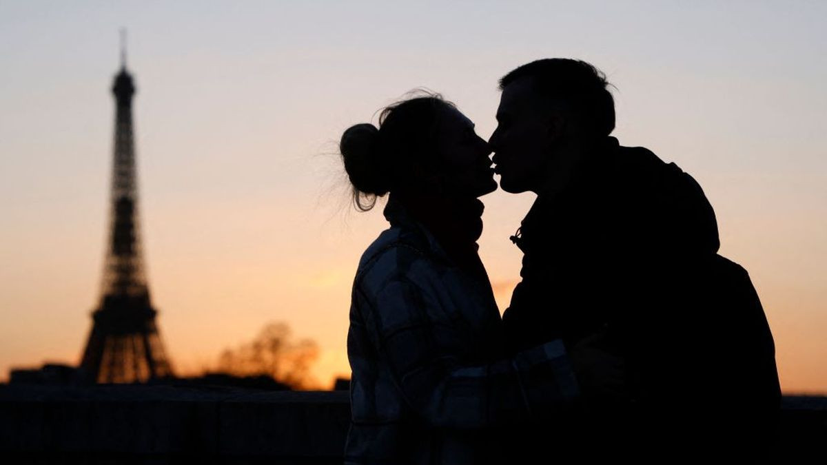 A couple kisses at sunset in front of the Eiffel Tower (L) on the La Concorde bridge over the Seine river in Paris. GETTY IMAGES.