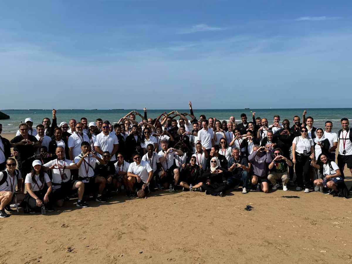 The Refugee Olympics Team gathers for a team photo on a beach of Normandy. OLYMPICS.COM.