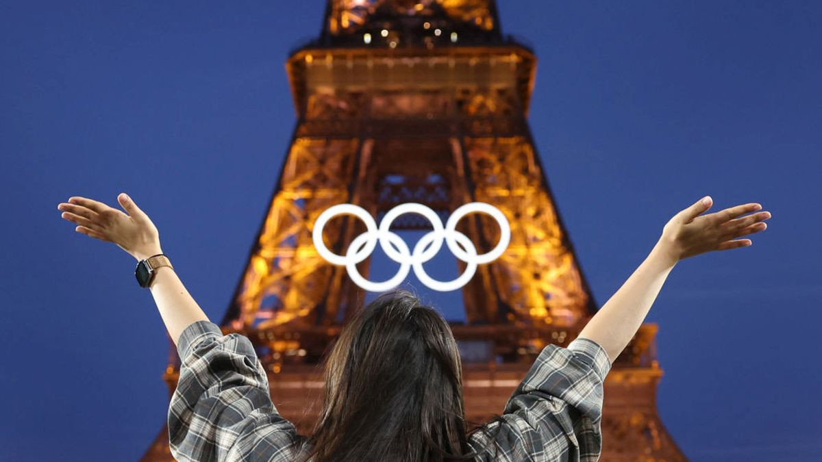 A spectator poses in front of the Eiffel Tower and the Olympic rings. GETTY IMAGES