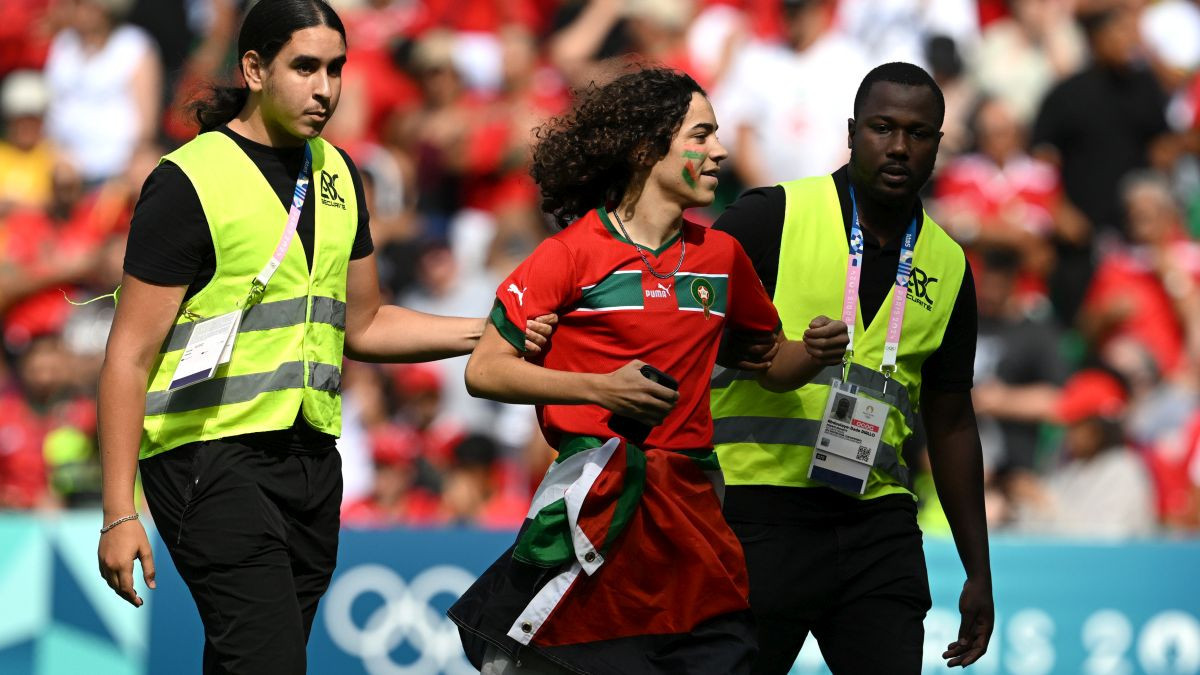 Stewards remove a pitch invader from the pitch during the match. GETTY IMAGES