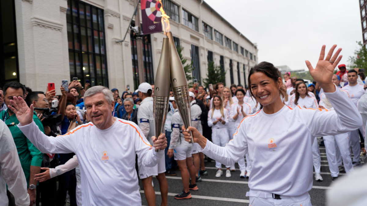 IOC president Thomas Bach and French handball player Cleopatre Darleux during the torch relay on 26 July 2024 in Paris. GETTY IMAGES