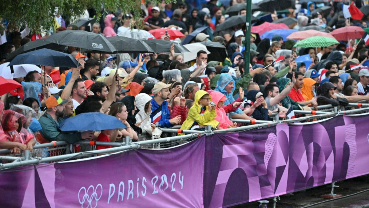 Spectators stand holding umbrellas during the opening ceremony of Paris 2024. GETTY IMAGES