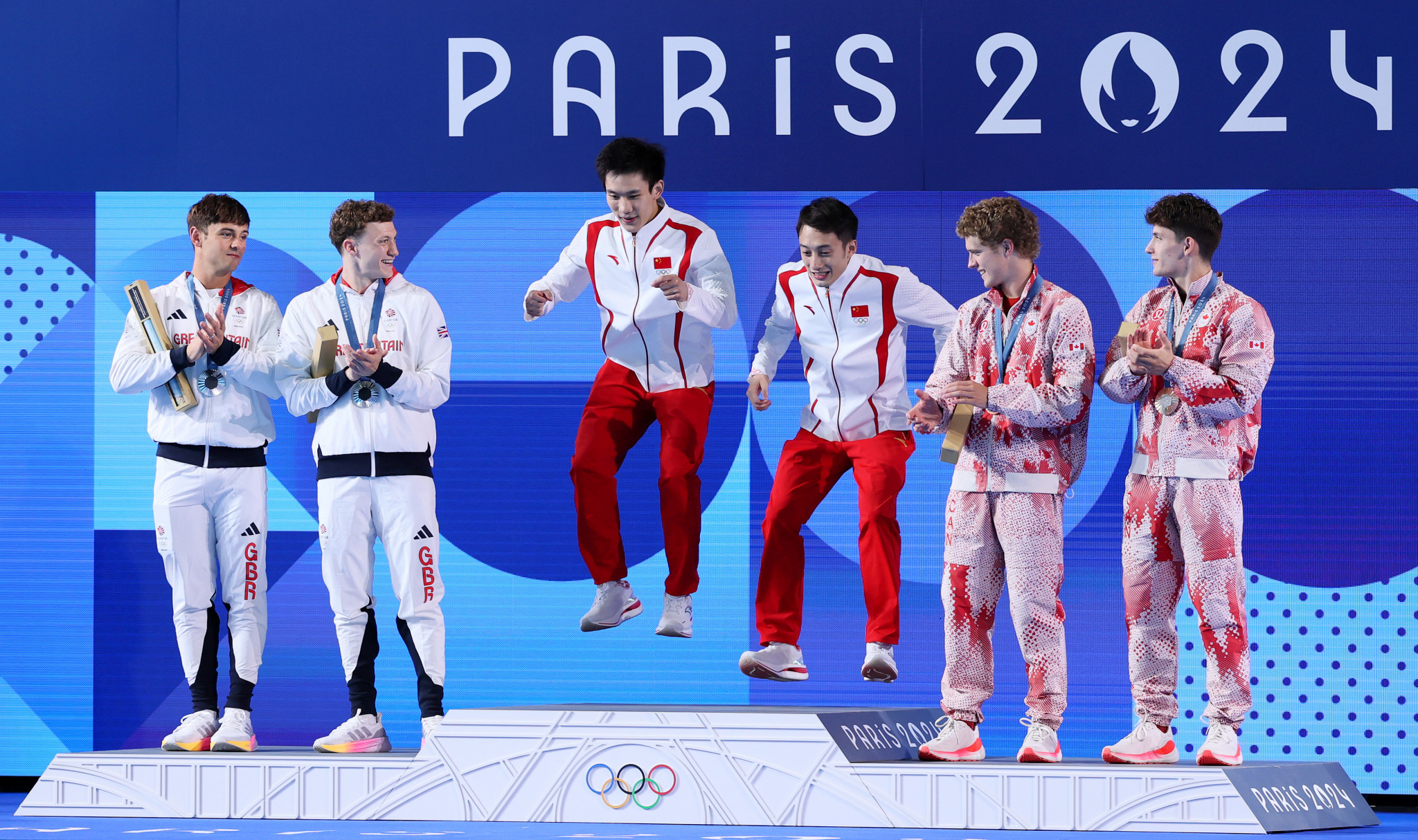 Gold Medalists Lian Junjie and Yang Hao of Team People's Republic of China on the podium alongside Silver Medalists Thomas Daley and Noah Williams of Team Great Britain and Bronze Medalists Rylan Wiens and Nathan Zsombor-Murray of Team Canada. GETTY IMAGES