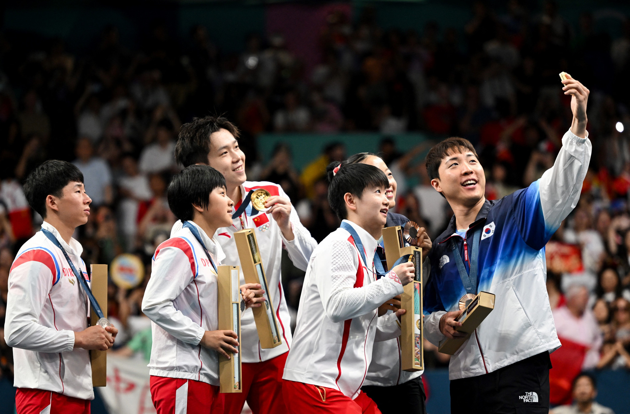 South Korea's Bronze medalist Lim Jonghoon takes a selfie with North Korea's silver medalists and China's gold medalists on the mixed table tennis doubles podium at the Paris 2024 Olympic Games. GETTY IMAGES