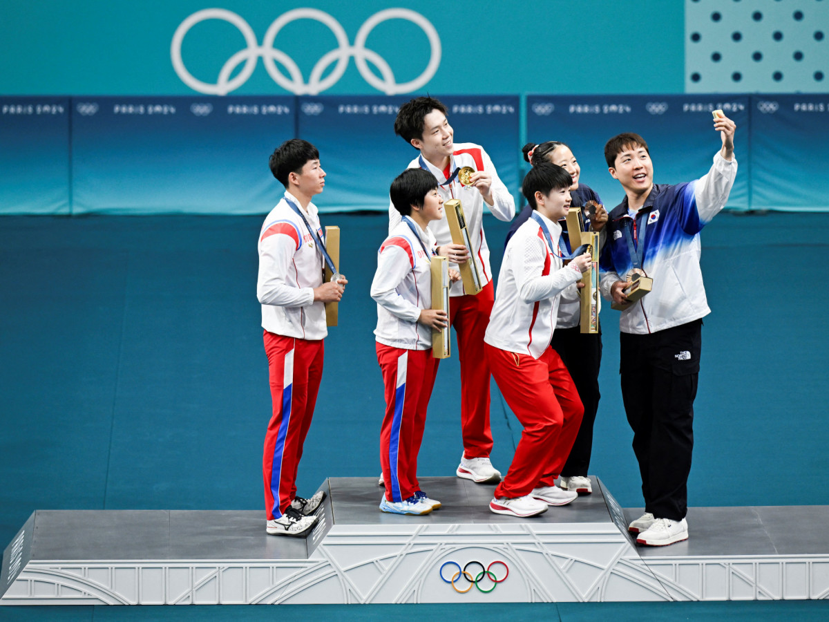 South Korea's Bronze medalist Lim Jonghoon takes a selfie with North Korea's silver medalists and China's gold medalists on the mixed table tennis doubles podium at the Paris 2024 Olympic Games. GETTY IMAGES