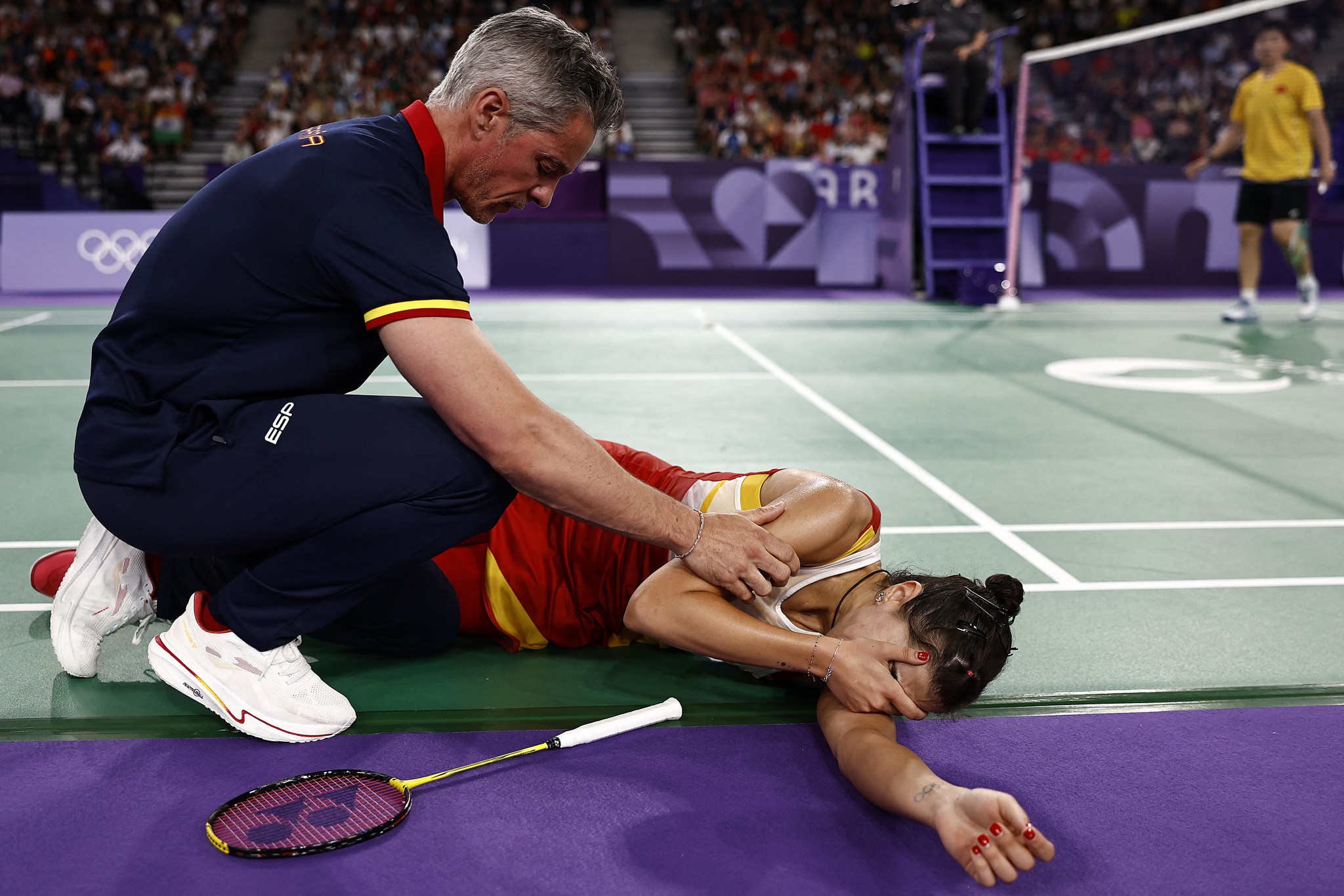 Carolina Marin is comforted by her coach while reacting from her injury in the women's singles badminton semi-final. GETTY IMAGES