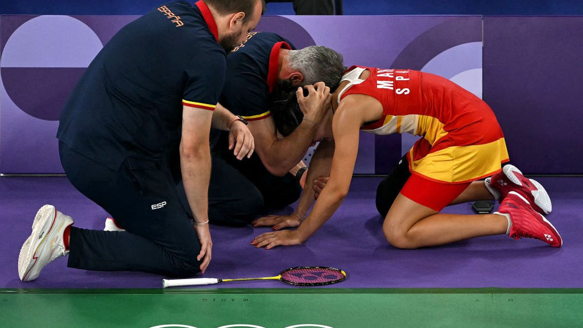 Spain's Carolina Marin is comforted by her coach Fernando Rivas as she concedes her women's singles badminton semi-final match against China's He Bing Jiao following an injury during the Paris 2024 Olympic Games at Porte de la Chapelle Arena in Paris on August 4, 2024. GETTY IMAGES