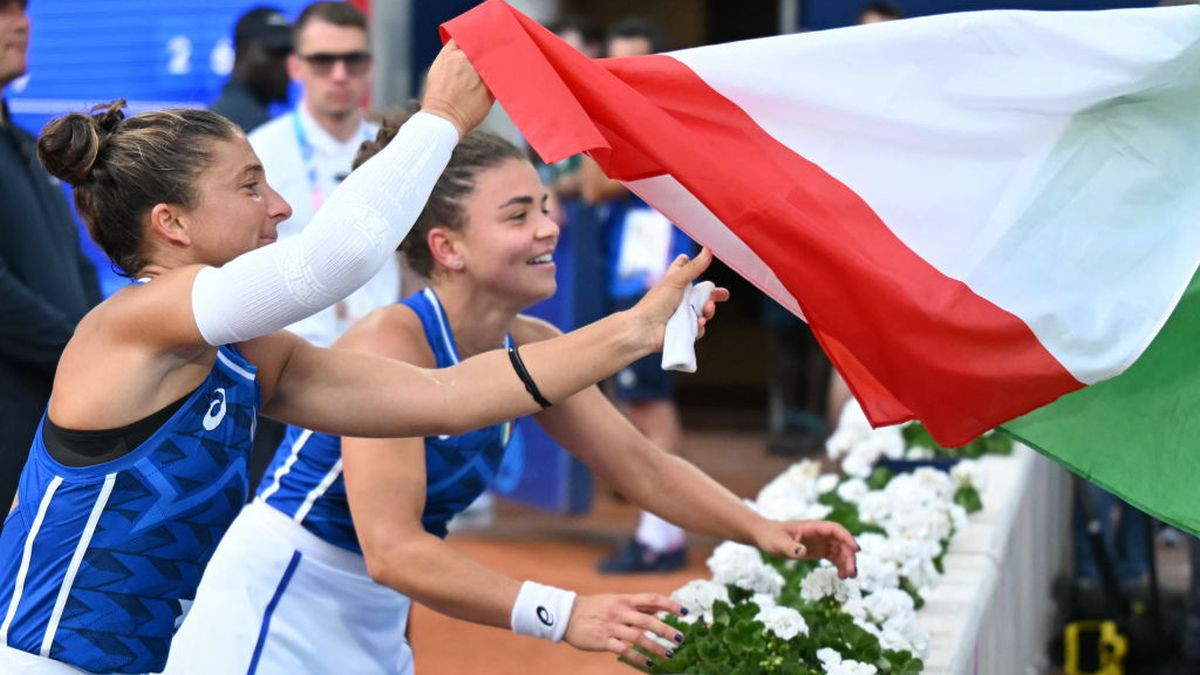 Sara Errani and Jasmine Paolini gather up an Italian flag as they celebrate the gold medal. GETTY IMAGES