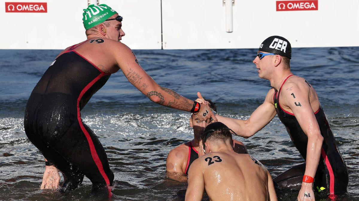 Several swimmers hug and congratulate each other upon reaching the finish line. GETTY IMAGES