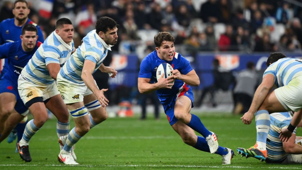 France's scrum half Antoine Dupont (C) runs with the ball as he is tackled during Paris 2024. GETTY IMAGES