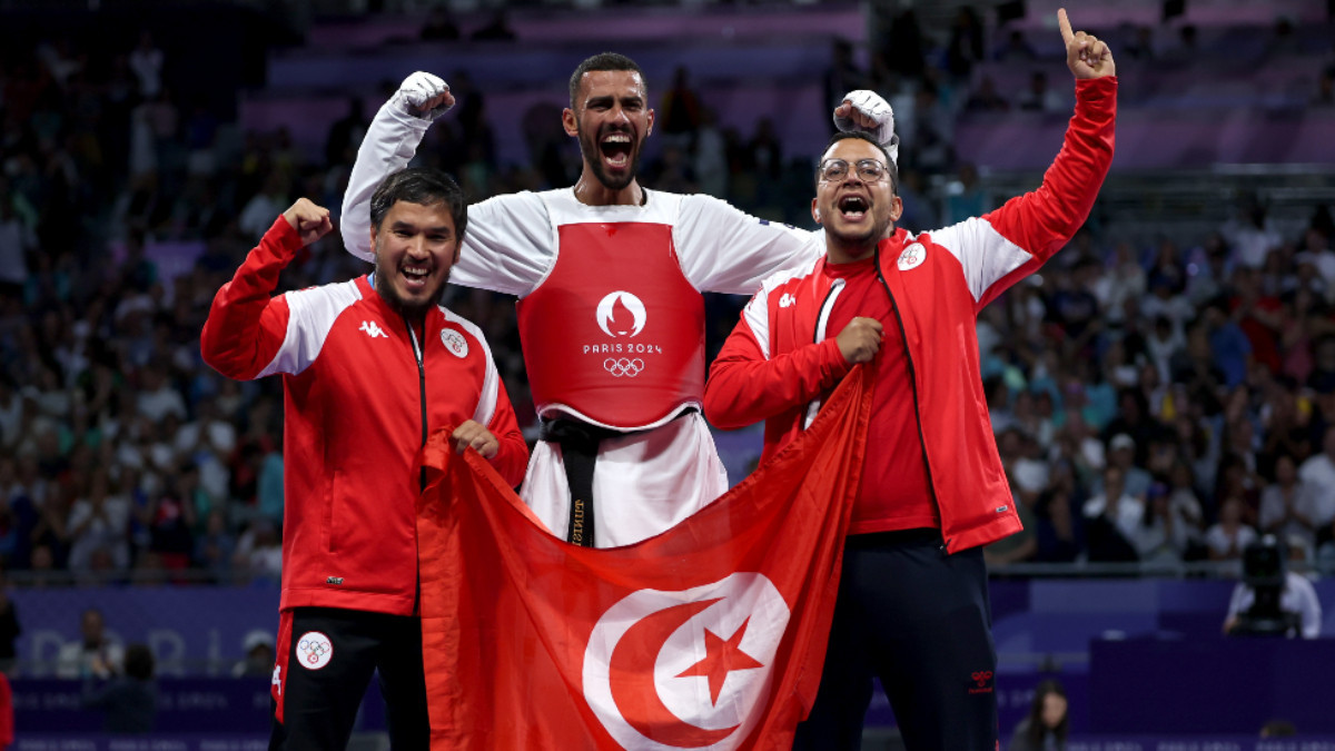 Firas Katoussi (in the centre) celebrating his victory with his coaches. GETTY IMAGES