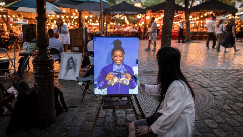 Simone Biles of Team United States posing with her Paris 2024 Olympic medals rojected projected an portrait artists canvas in Montmartre. GETTY IMAGES