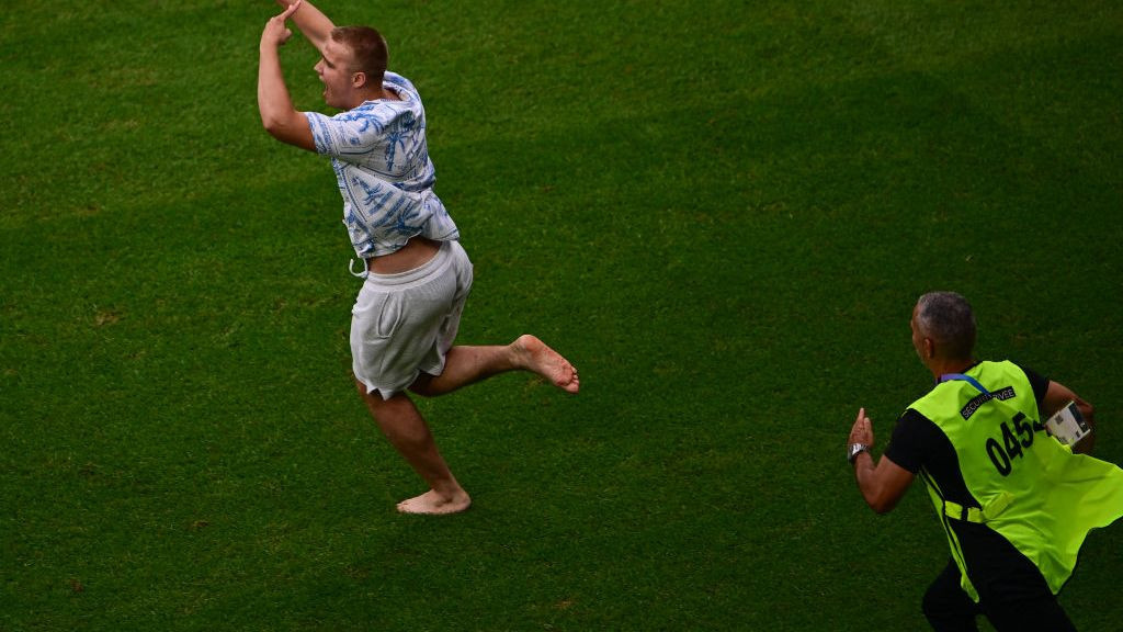 A pitch invader runs away from a security guard following the men's group B football match between Ukraine and Argentina . GETTY IMAGES